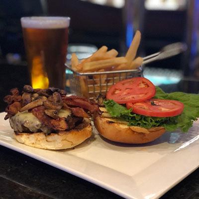 cheeseburger with mushrooms bacon lettuce and tomato accompanied by fries and beer
